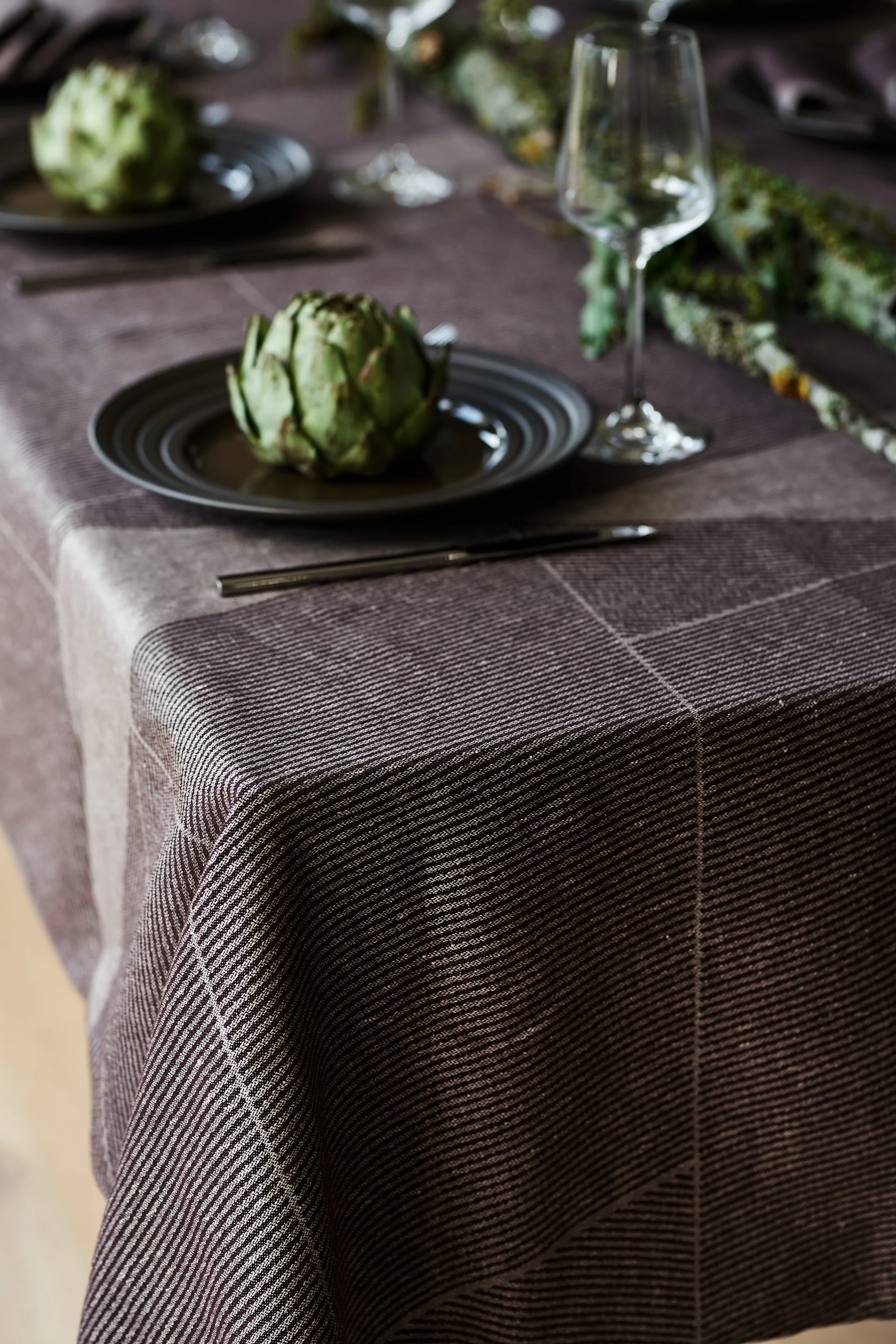A brown table cloth from NJRD with the brown Lines plate also from NJRD on an elegant and rustic table setting.