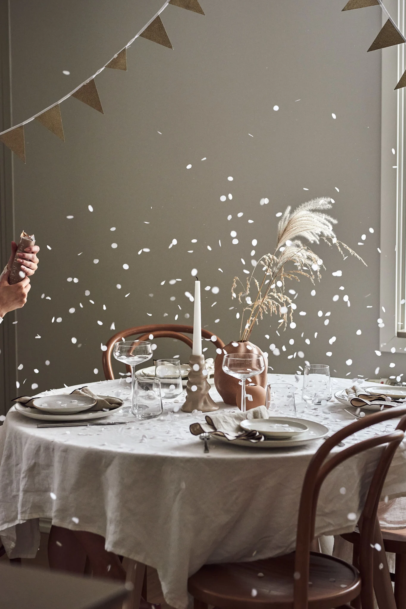 How to throw a party with the perfect atmosphere, here you see a set table with a recently exploded party popper and the confetti settling on the table. 
