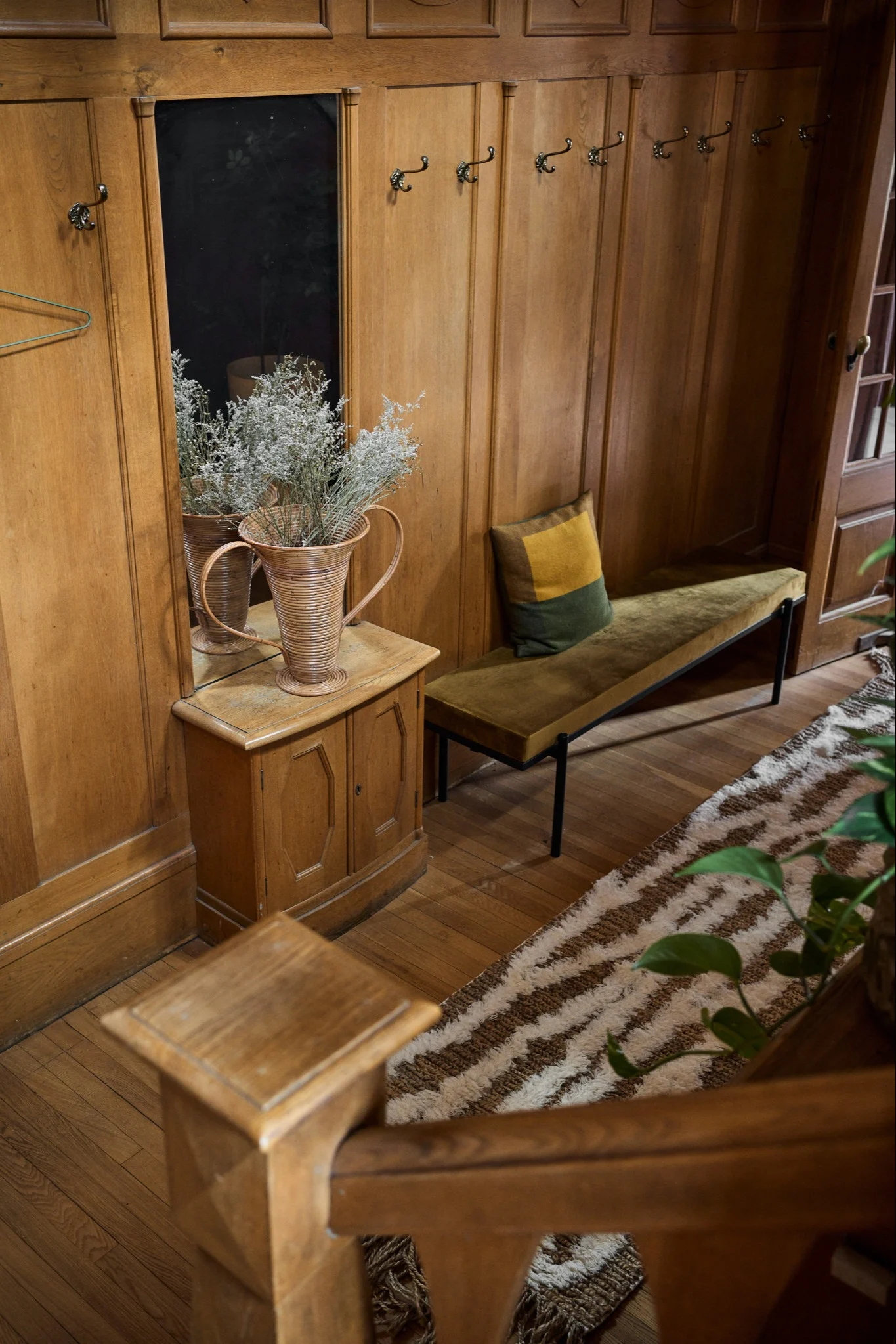 A wooden staircase with a bench and a patterned rug beside it, conveying a nostalgic home and reflecting the interior design trends of 2026.