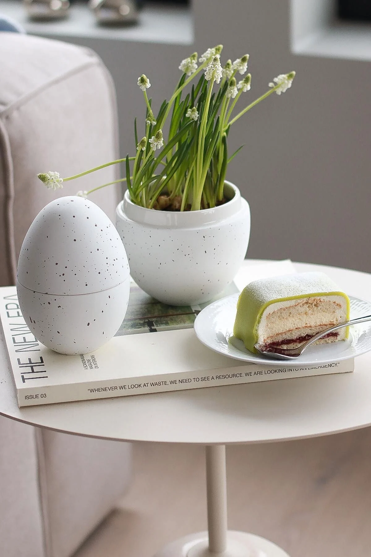 On a side table stands the white bonbonnière with flowers in it from Cooee Design, next to it a plate with Princesstarta, in the home of @picsbyellen.