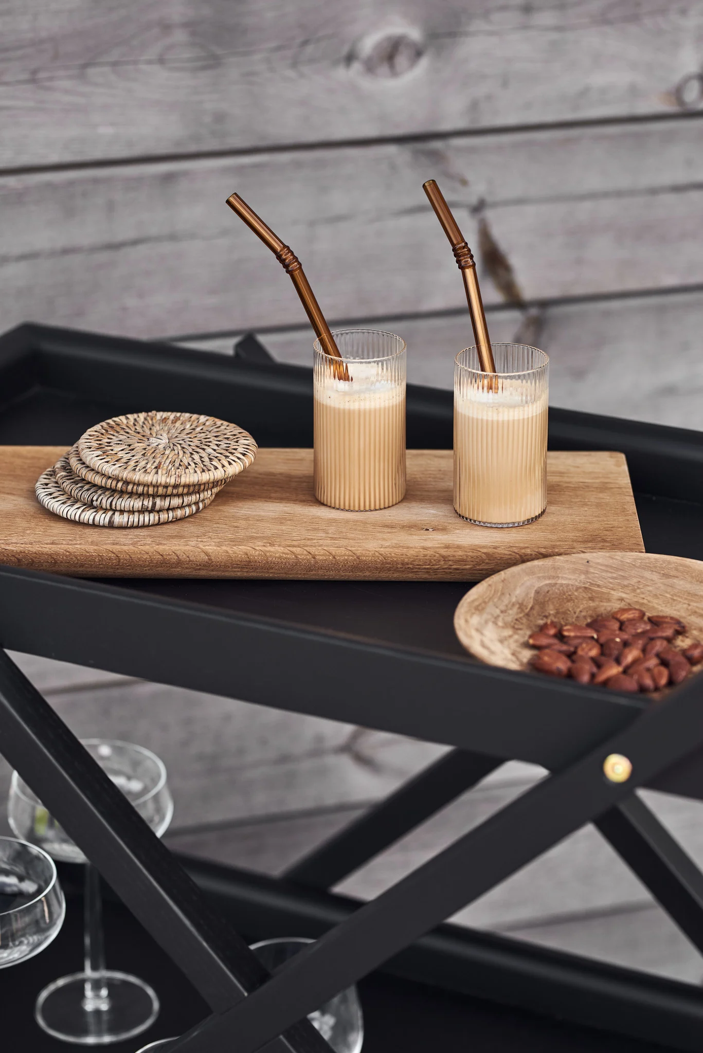 Discover a summer recipe for a cold vanilla latte. Here you see two glasses of latte on a wooden tray on top of a black trolley from Design House Stockholm. 