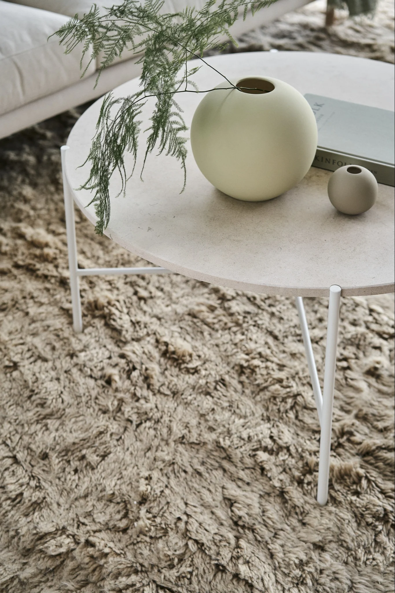 The iconic Ball vase in shell and sand from Cooee Design on a coffee table in a Scandinavian style living room.