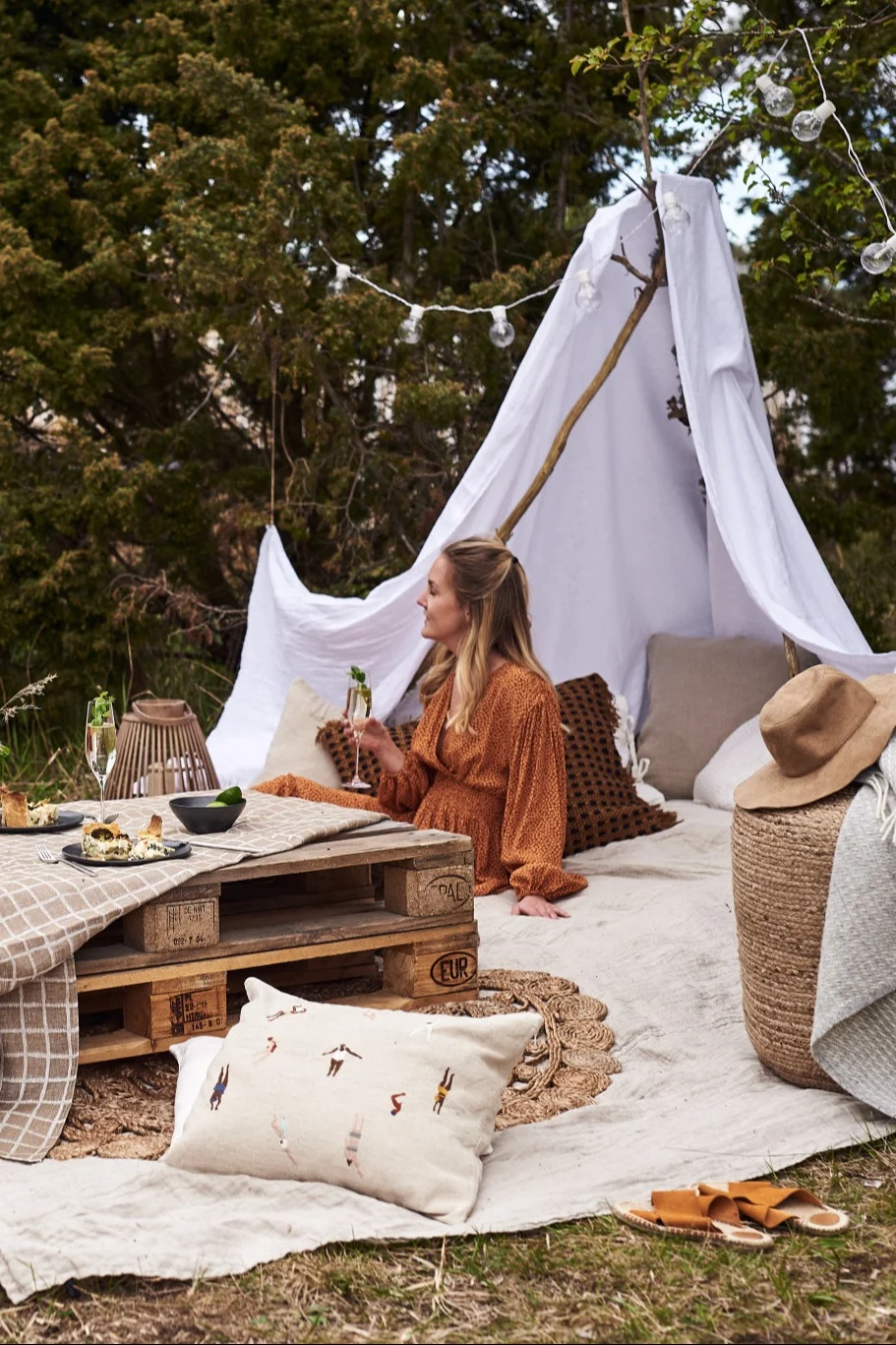 Add glamping in the garden to your summer bucket list. Here you see a woman sitting under a homemade tent. 