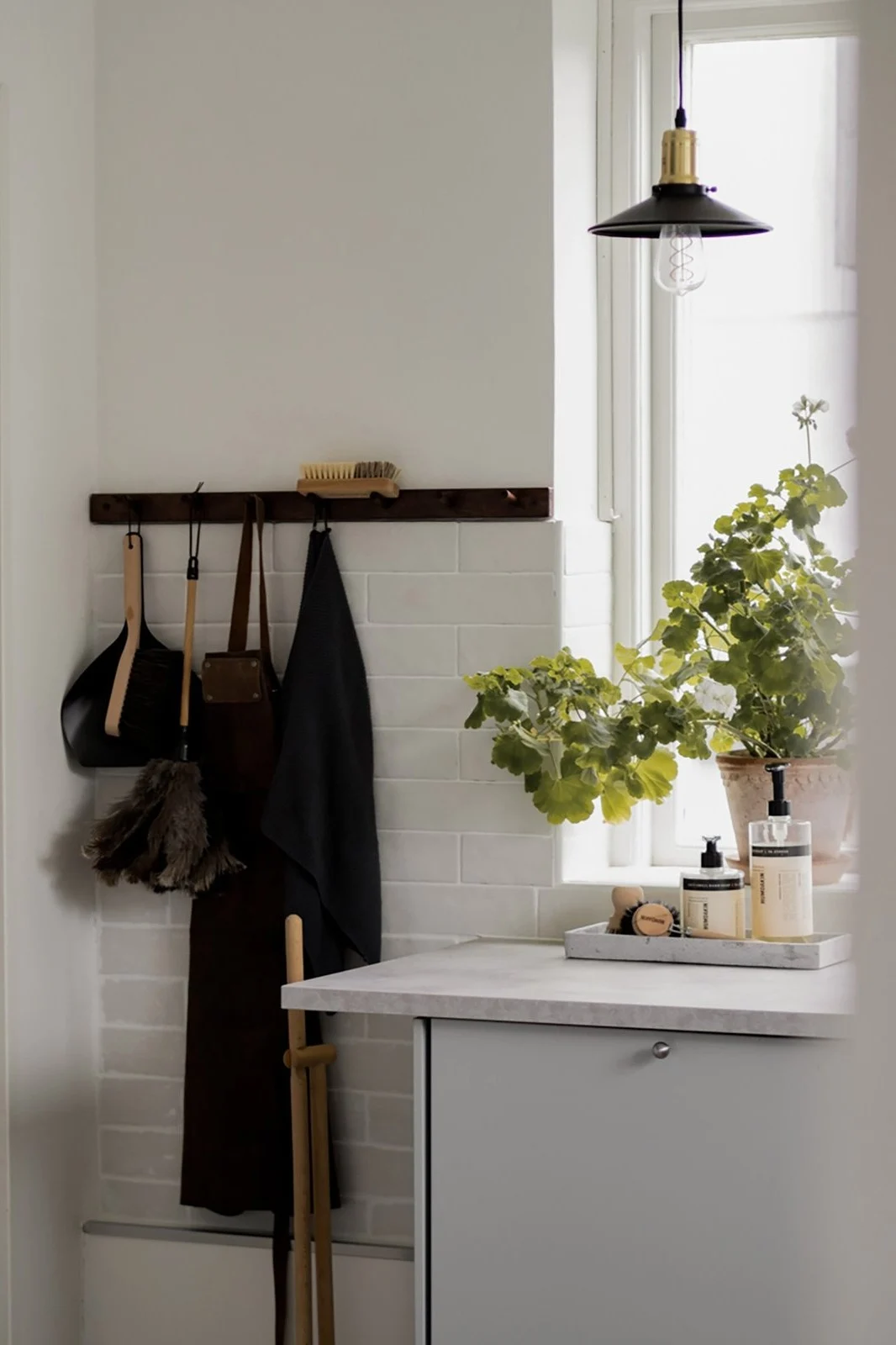 Smaller pendant lights provide spot lighting in the kitchen. Here you can see the Disc Mini pendant light in black from Globen Lighting hanging in a kitchen in front of a window.