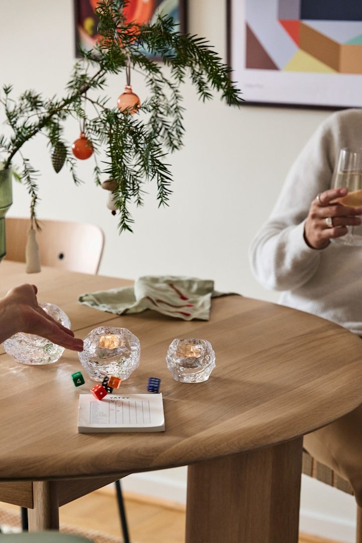 A hand rolls dice during a game of Yatzee from HAY, part of the vintage Christmas decor. 