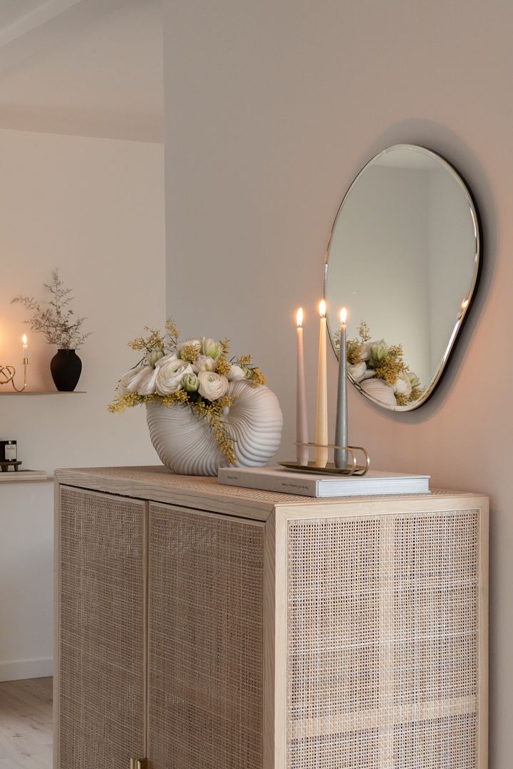 Create a Scandinavian home with @haus_tannenkamp, here you see a rattan cupboard with the Pond mirror and shell vase both from ferm living. 