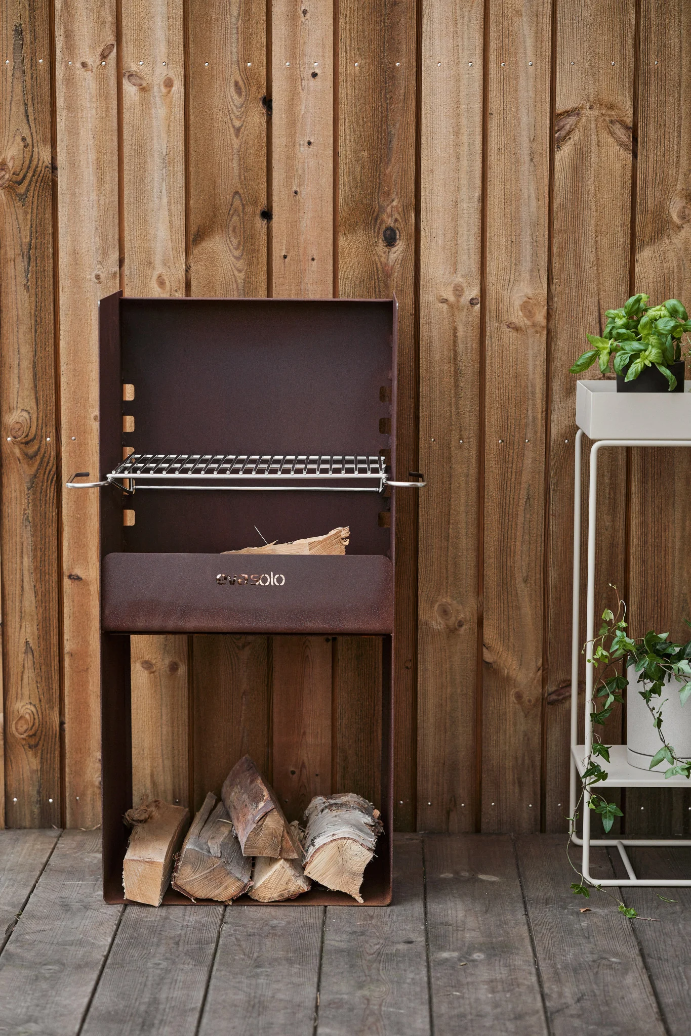 The rustic FireSpot barbecue from Eva Solo stands on a wooden patio.