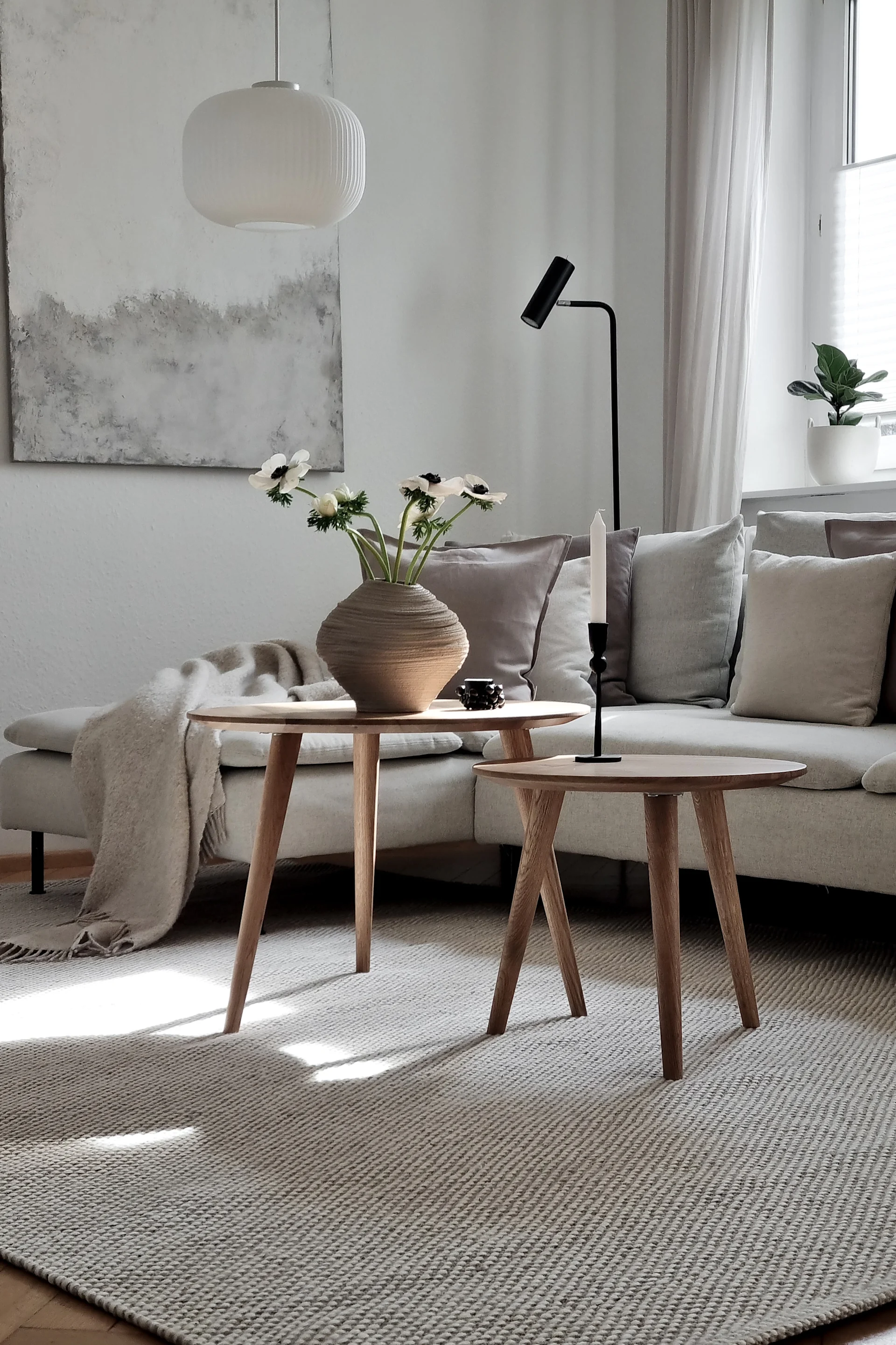 Create a cosy hygge living room with grey tone on tone with natural elements like a wooden coffee table or wool carpet as you see here.