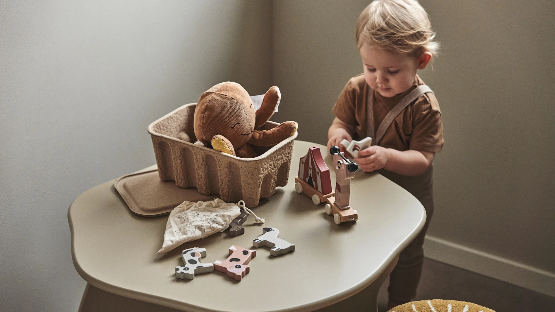 A child plays with wooden toys that have come from a paper storage box, friendly ideas for the children's room. 