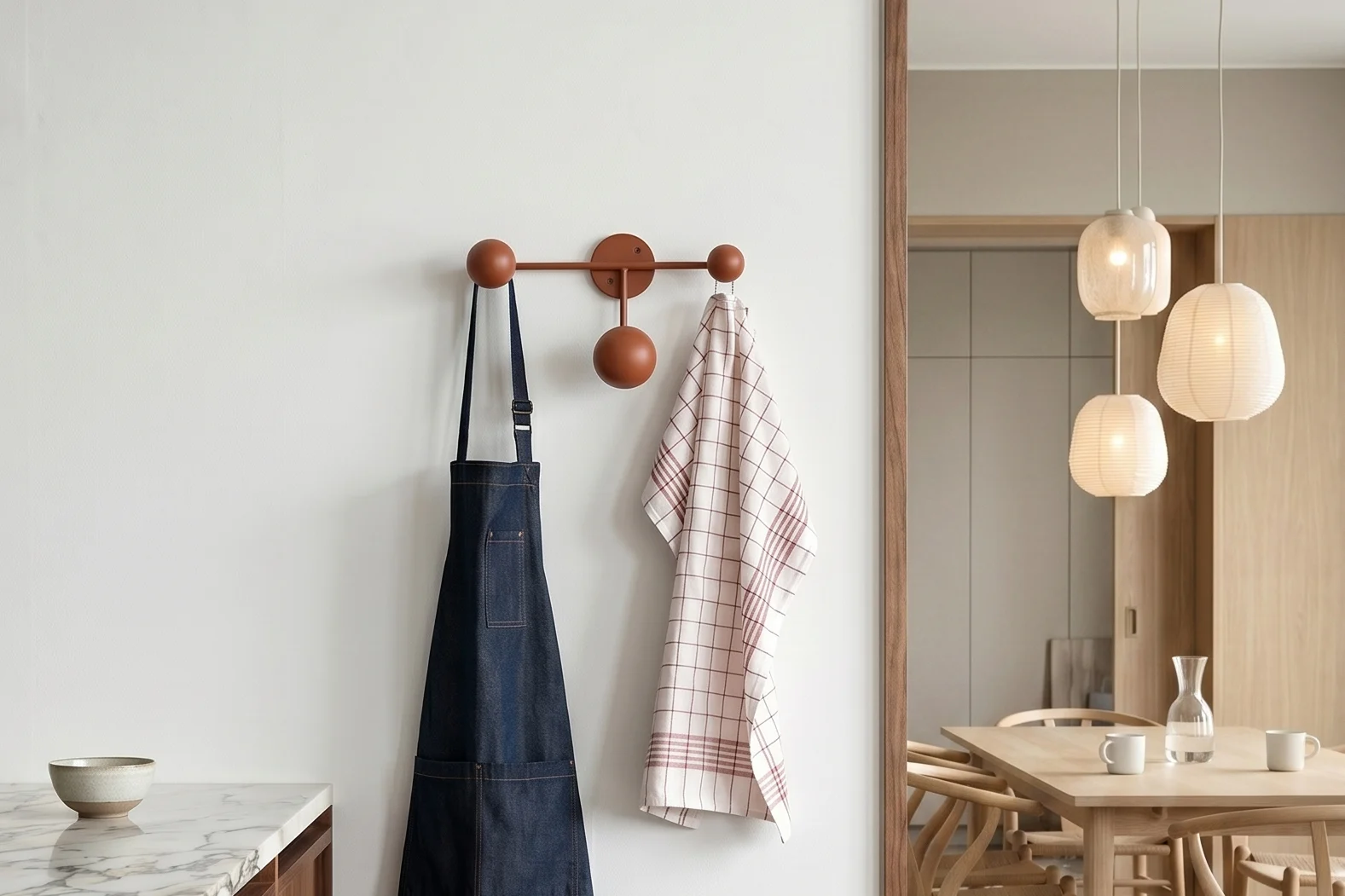 Kitchen with marble. Blue apron, plaid towel on rack. Dining room with table and pendant lights.