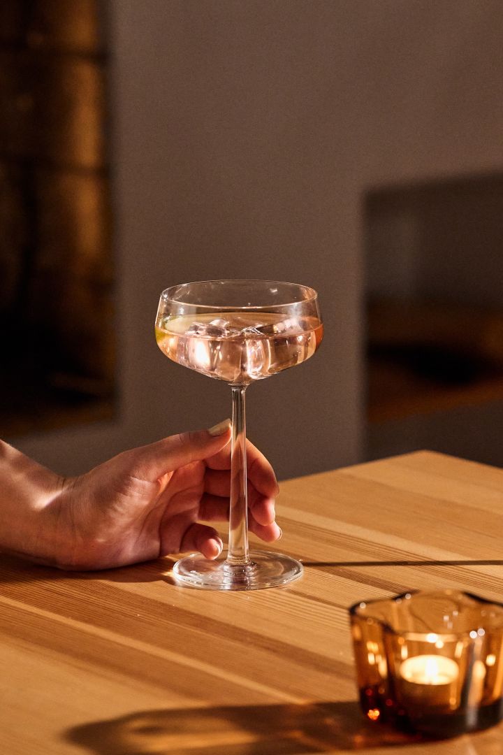 Christmas gift ideas for your mum, dad, sister or brother, here a hand holds the coupe champagne glass Essence from Iittala. 
