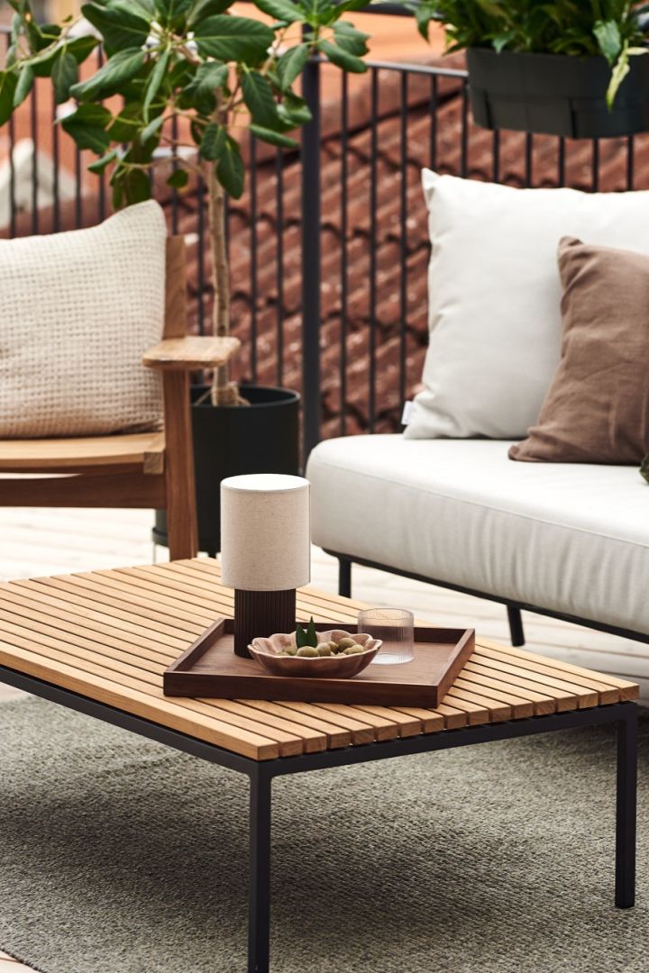 The cordless table lamp, Manhattan from &Tradition on a wooden table on a balcony.