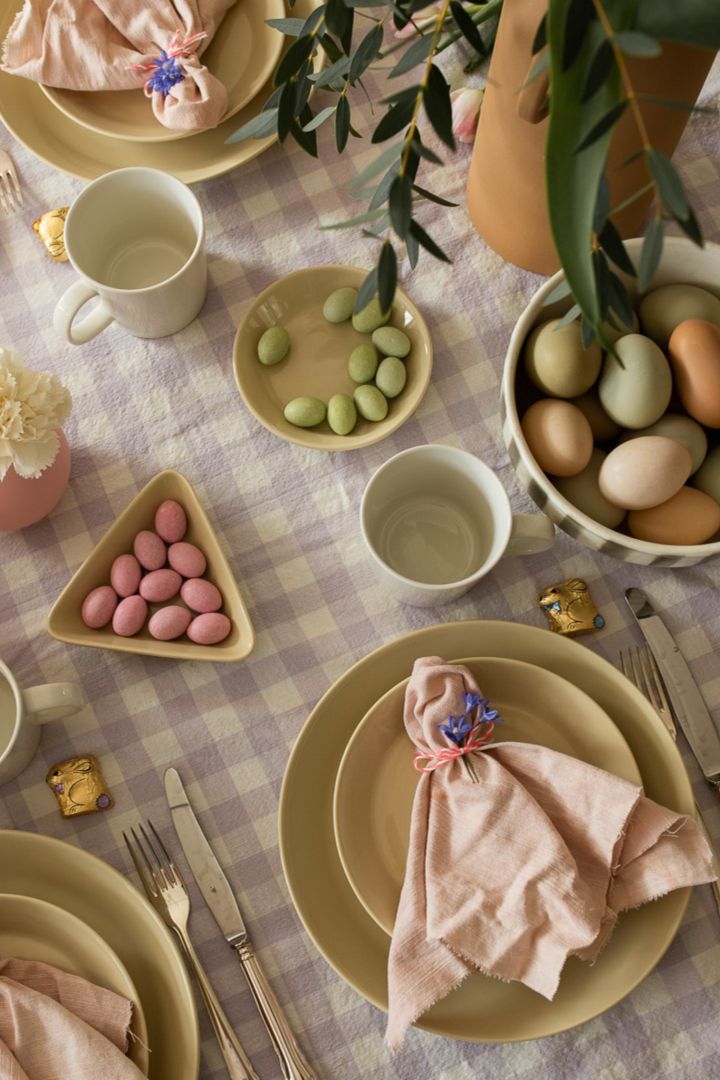 Great Easter table setting ideas always include a lovely napkin fold like you see here with a simple scrunch and flower wrapped around a Scandi Living linen napkin in pink. 