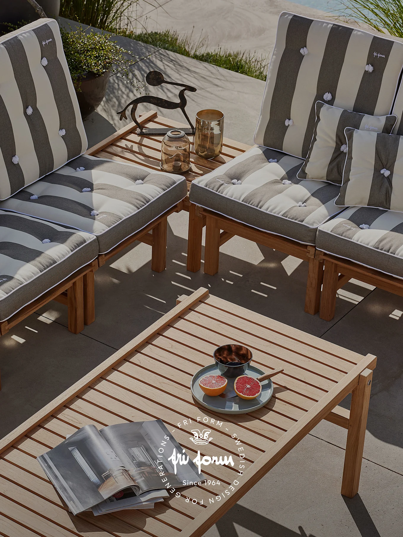 An outdoor patio with wooden lounge chairs featuring striped cushions, a coffee table with a magazine, grapefruit, and a bowl.