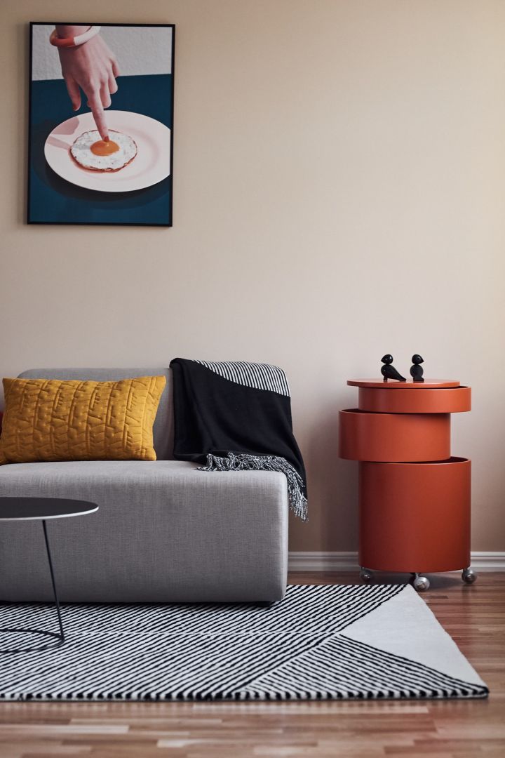 Colour blocking in your interior is just right according to the colour trends 2022 - here in a living room with black and white carpet from NJRD, yellow pillow and red serving trolley.