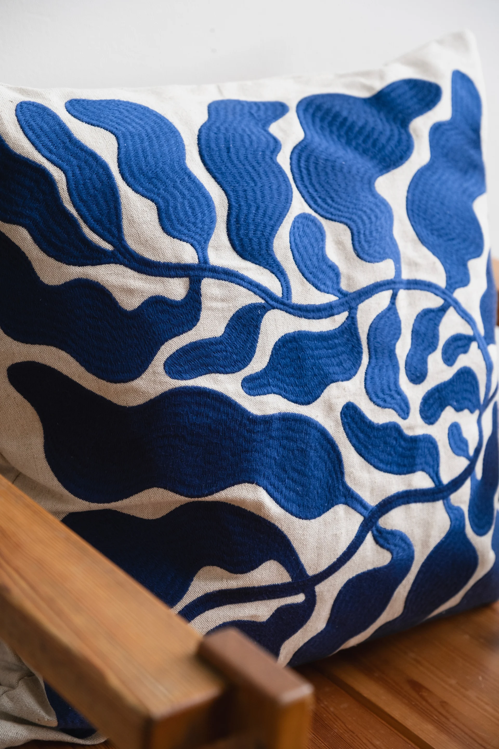 A cushion embroidered with a blue floral pattern that reflects the interior design trends of 2026.