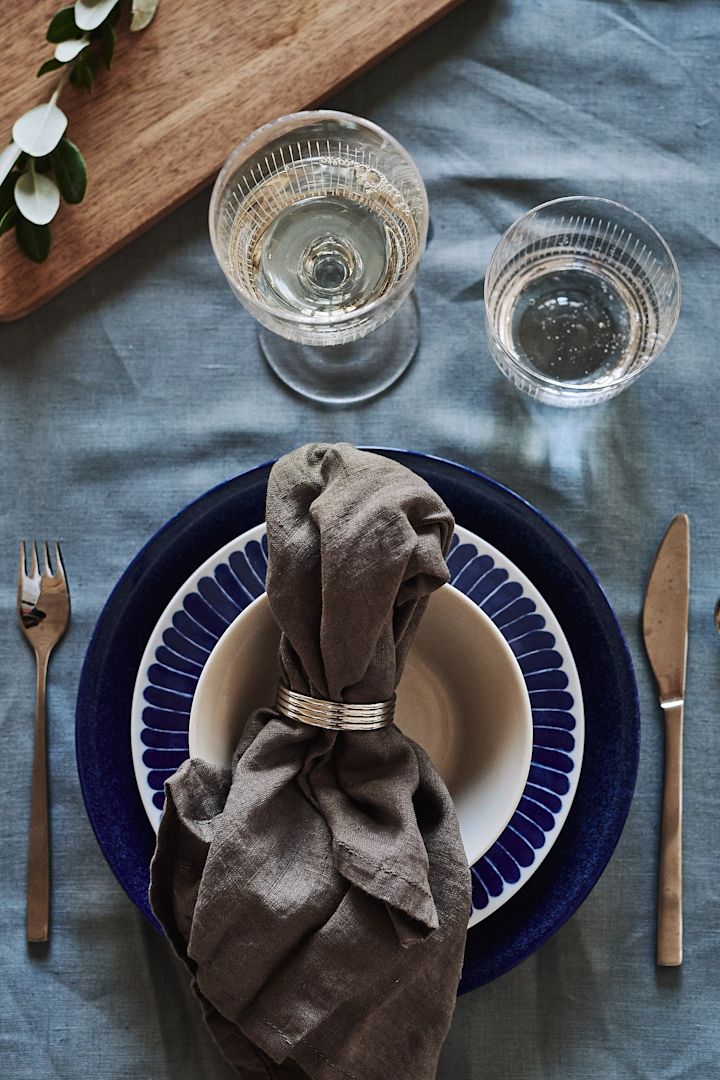 A blue and white table setting welcomes guests to the table with its grain blue shade and plate from Iittala, Götefors porcelain and Nordic Nest.