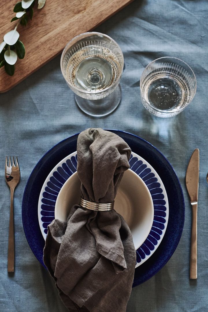 A blue and white table setting welcomes guests to the table with its grain blue shade and plate from Iittala, Götefors porcelain and Nordic Nest.