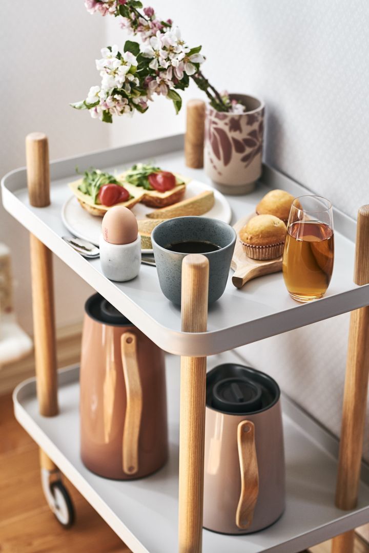 A real luxury breakfast with coffee, eggs and sandwiches is served on a side table for a delicious breakfast in bed.