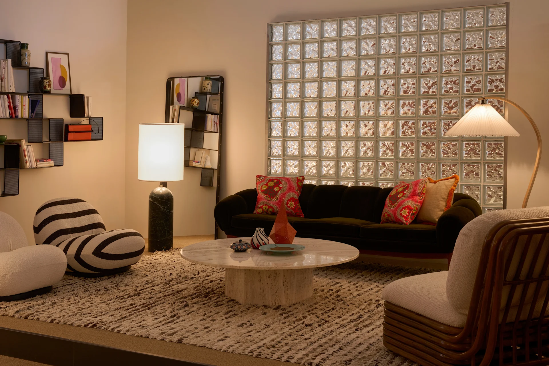 A stylish retro living room with a velvet sofa, marble coffee table, shag rug, unique chairs, lamps, and a glass block wall.