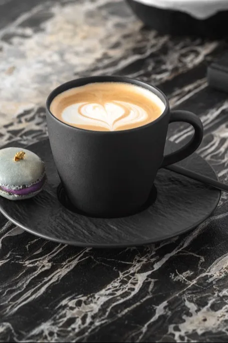 A black coffee cup with a foam milk art on top. 