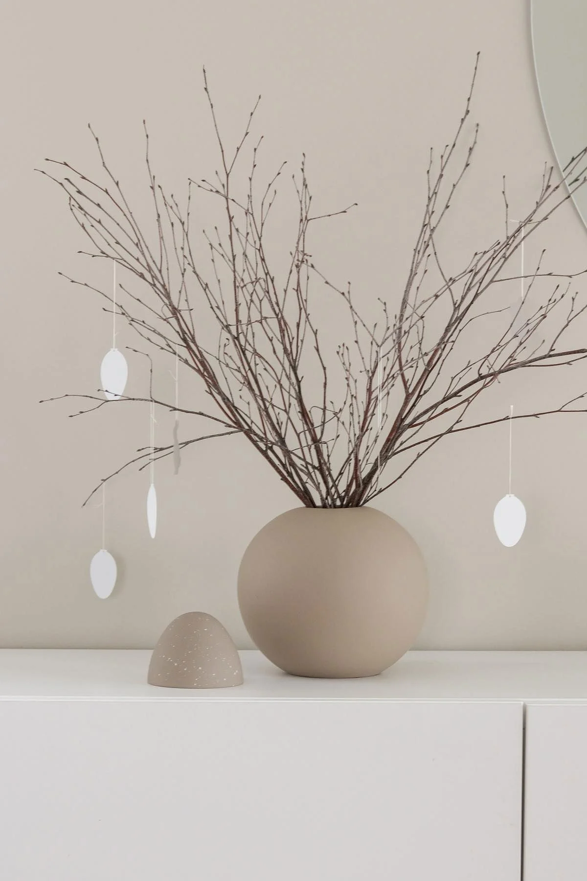 An Easter bush also stands on a white dresser in a sand-coloured ball vase with Easter Deco egg pendants, both from Cooee Design, in @tunadalen's home.
