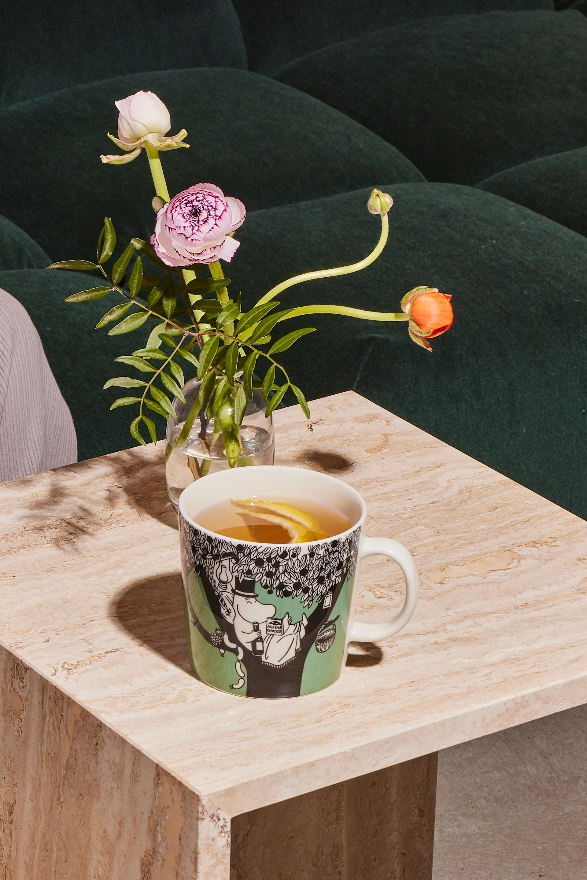 The green Moomin cup stands on a coffee table with coffee.