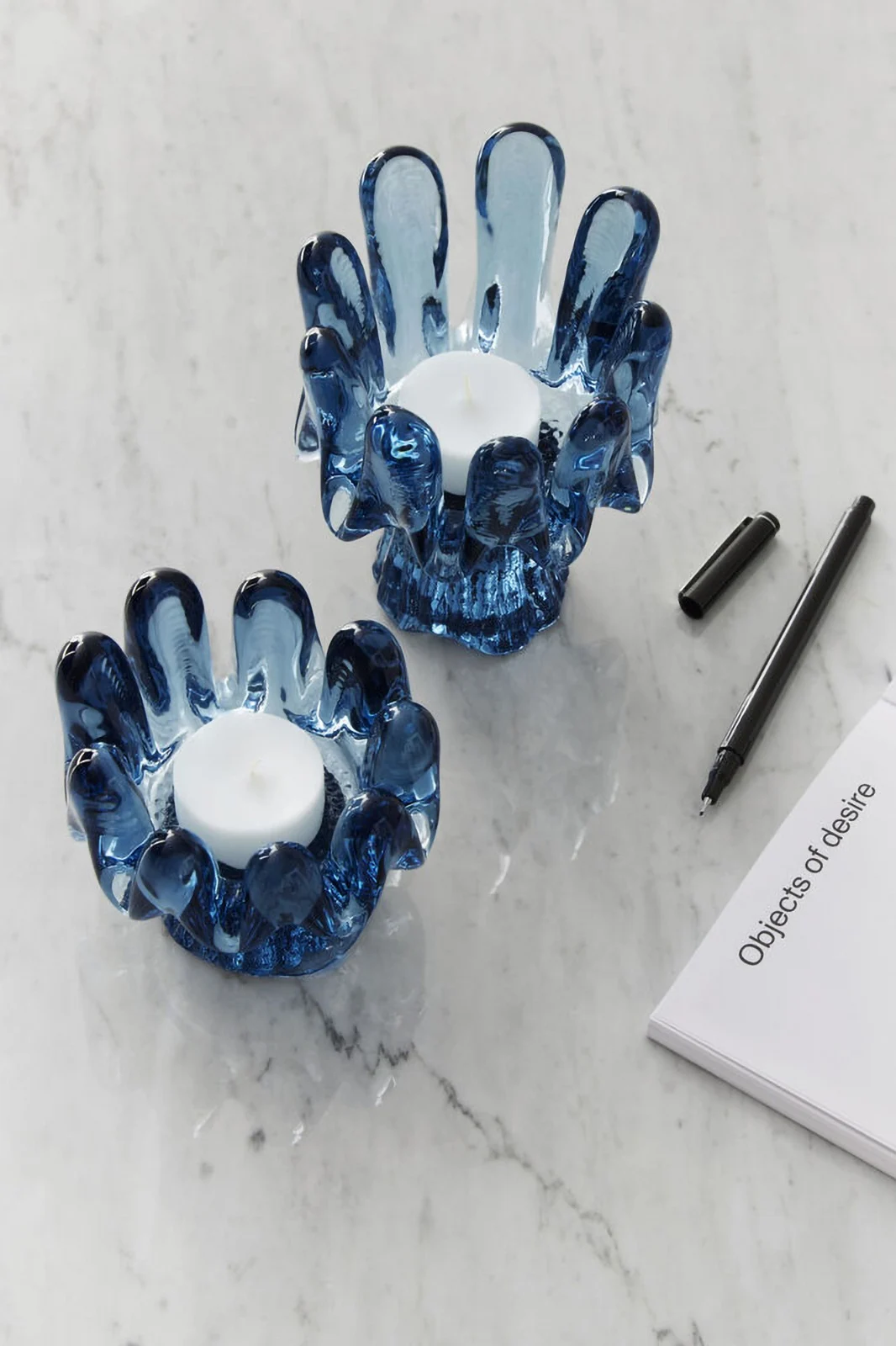 Interior design trends 2025: Two blue candle holders from the Solros collection by Kosta Boda stand on a light-coloured table.