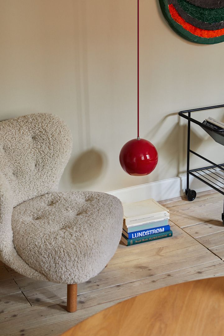 Topan ceiling light in the colour vermillion red hung near the floor to spotlight a specific area in the living room.