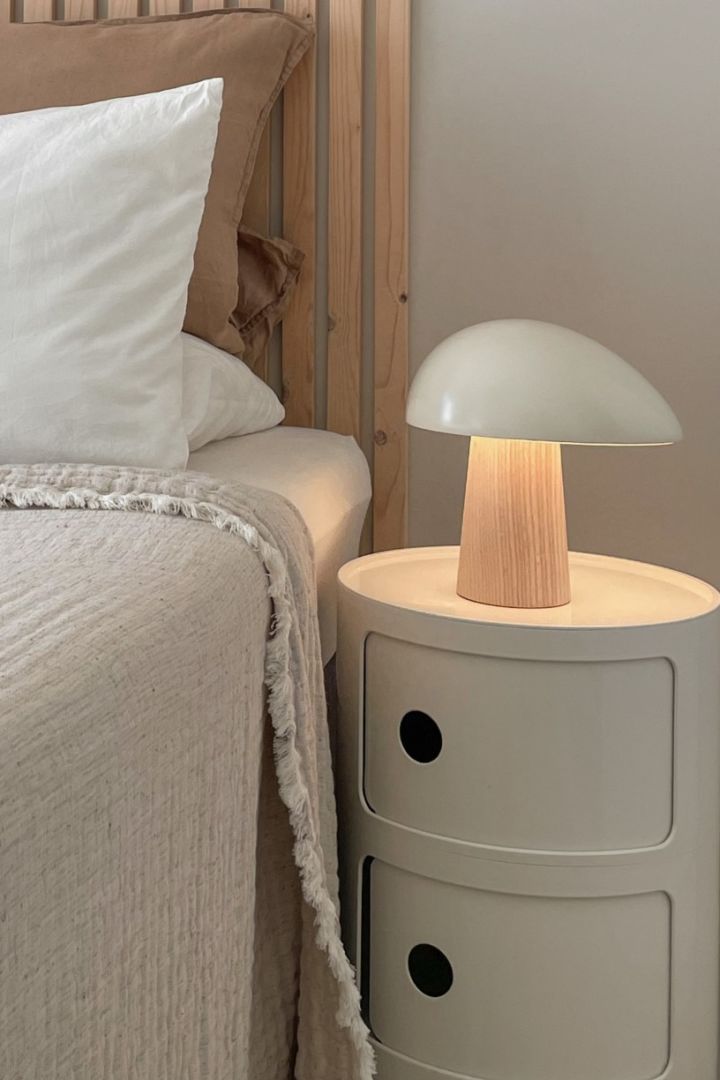 The Night Owl table lamp from Fritz Hansen creates the perfect cosy glow in natural wood for a Scandinavian bedroom.