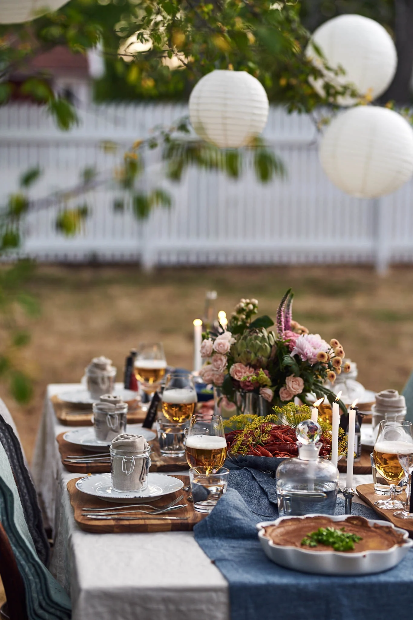 Swedish crayfish party: Set an outdoor table and decorate it with lanterns, plates and flowers.