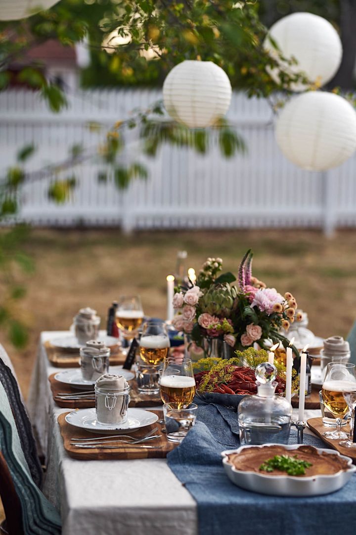 Swedish crayfish party: Set an outdoor table and decorate it with lanterns, plates and flowers.