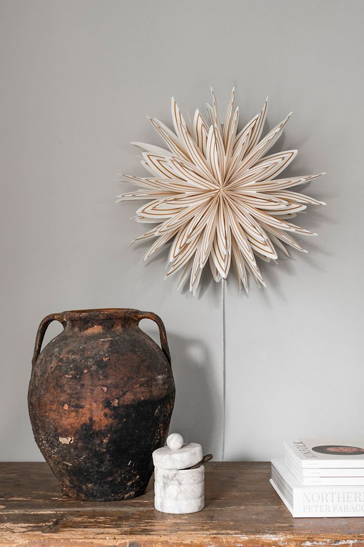 The Lovisa Christmas star from Watt & Veke hangs on the wall above a rustic shelf.