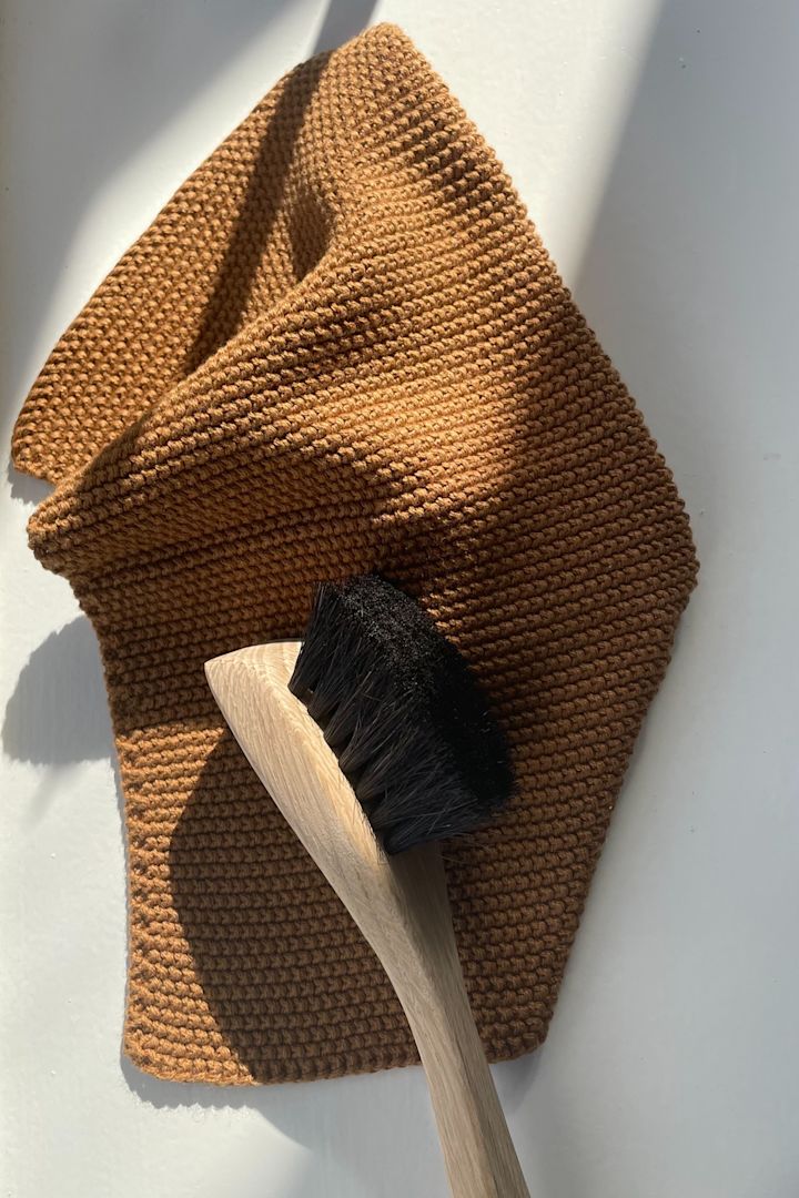 Clean your frying pan with a dishwashing brush, shown here on a brown dishcloth, both from Humdakin.