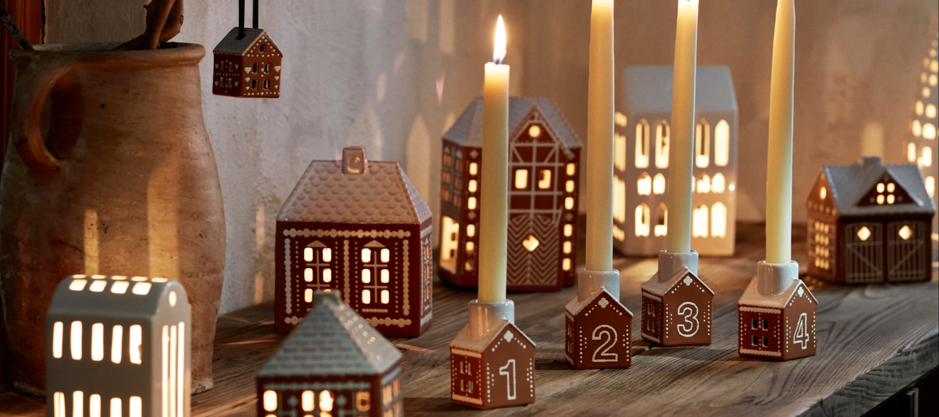 How to decorate with traditional Scandinavian Christmas decorations - here you see a young boy eating a gingerbread house on the windowsill surrounded by other Gingerbread house style candle holders.