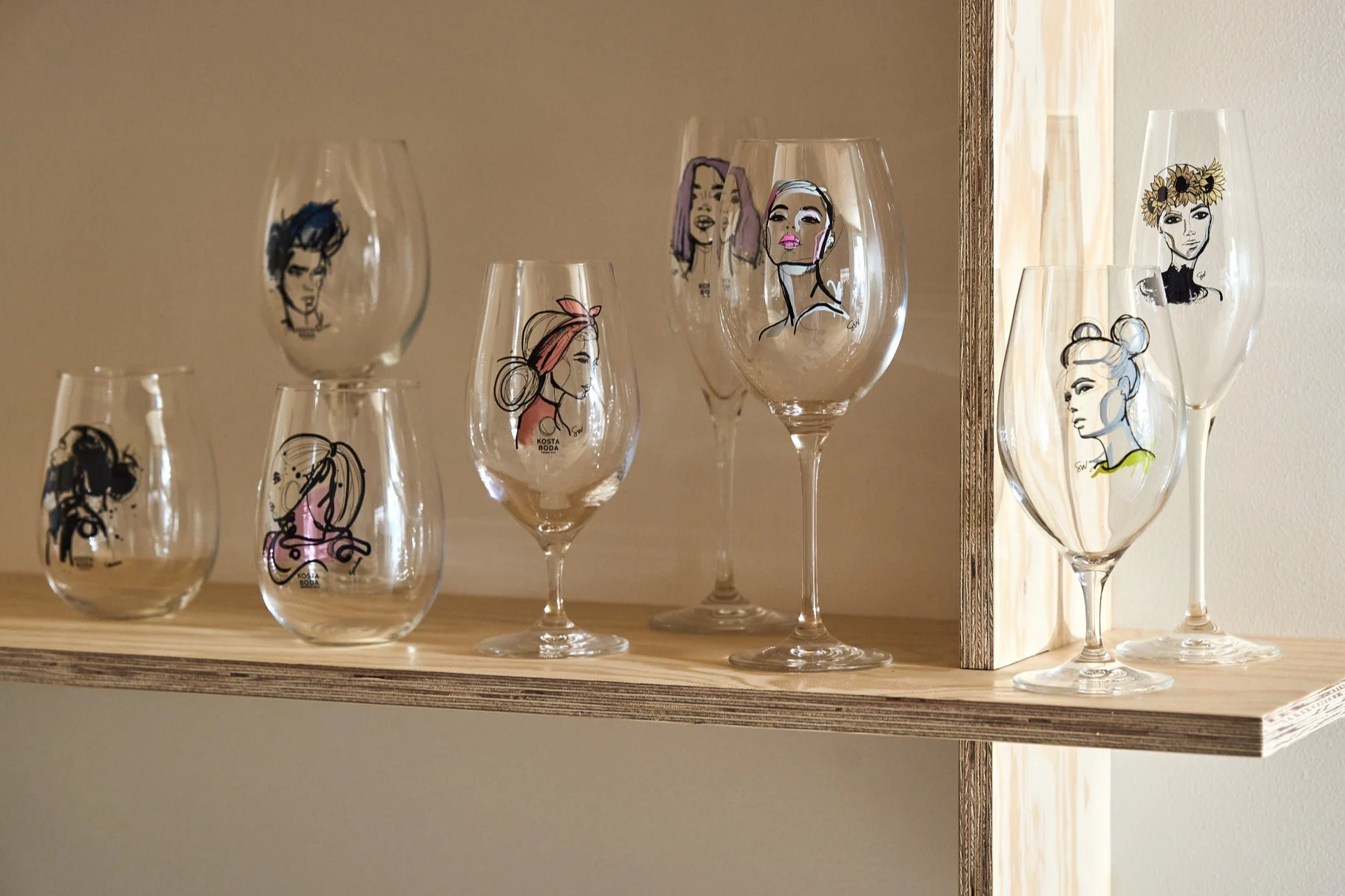 A collection of glasses from the All about you collection stand on a plywood shelf.  
