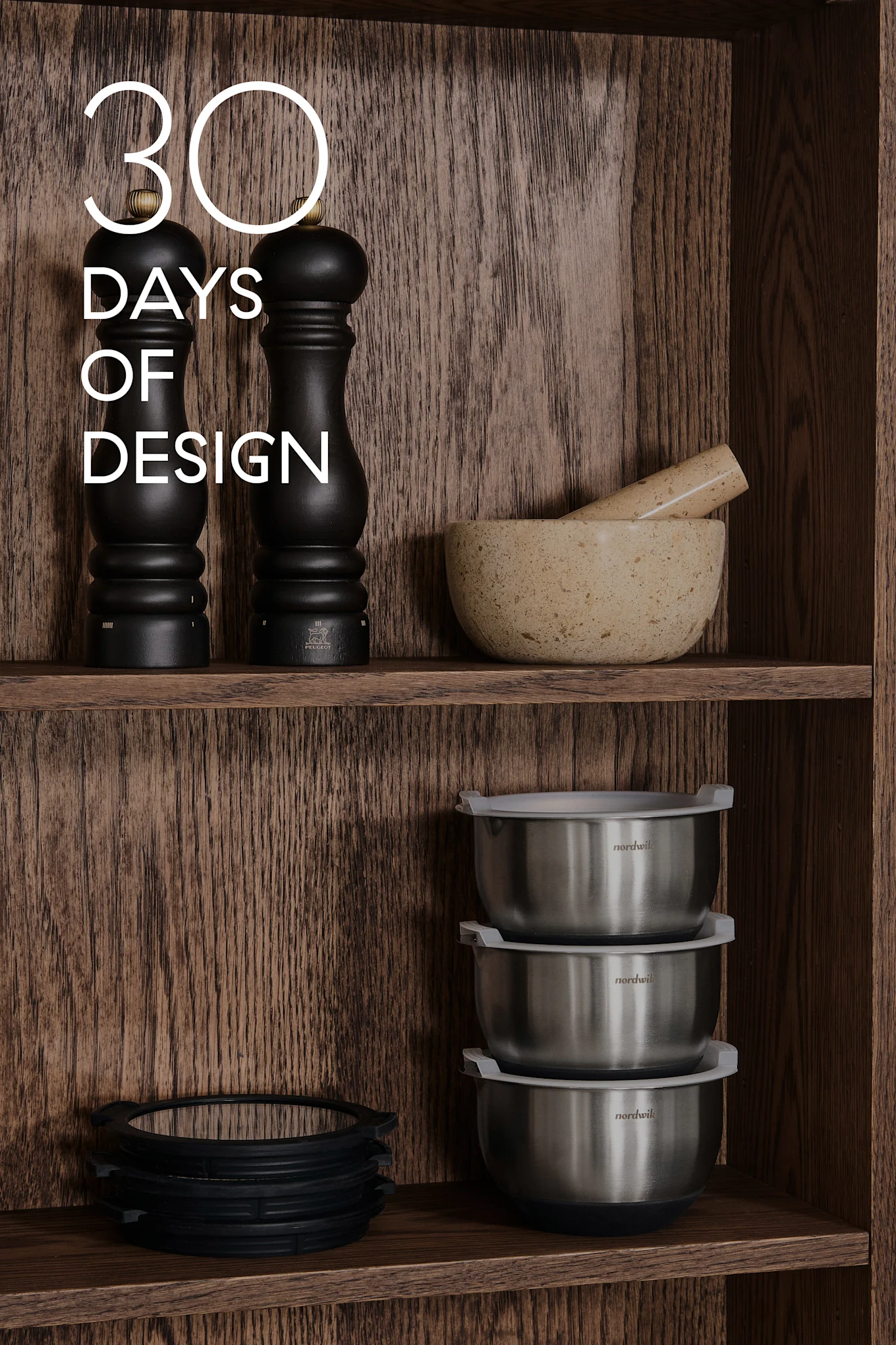 Wooden shelves with kitchenware: black mills, mortar & pestle, steel bowls, silicone rings. Text: 30 DAYS OF DESIGN.