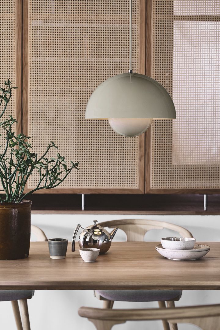 Enjoy the Japandi trend with simple clean accessories like the VP7 hanging Flowerpot lamp from &tradition in greige, here you see it hanging in a dining room setting with a rattan wall. 