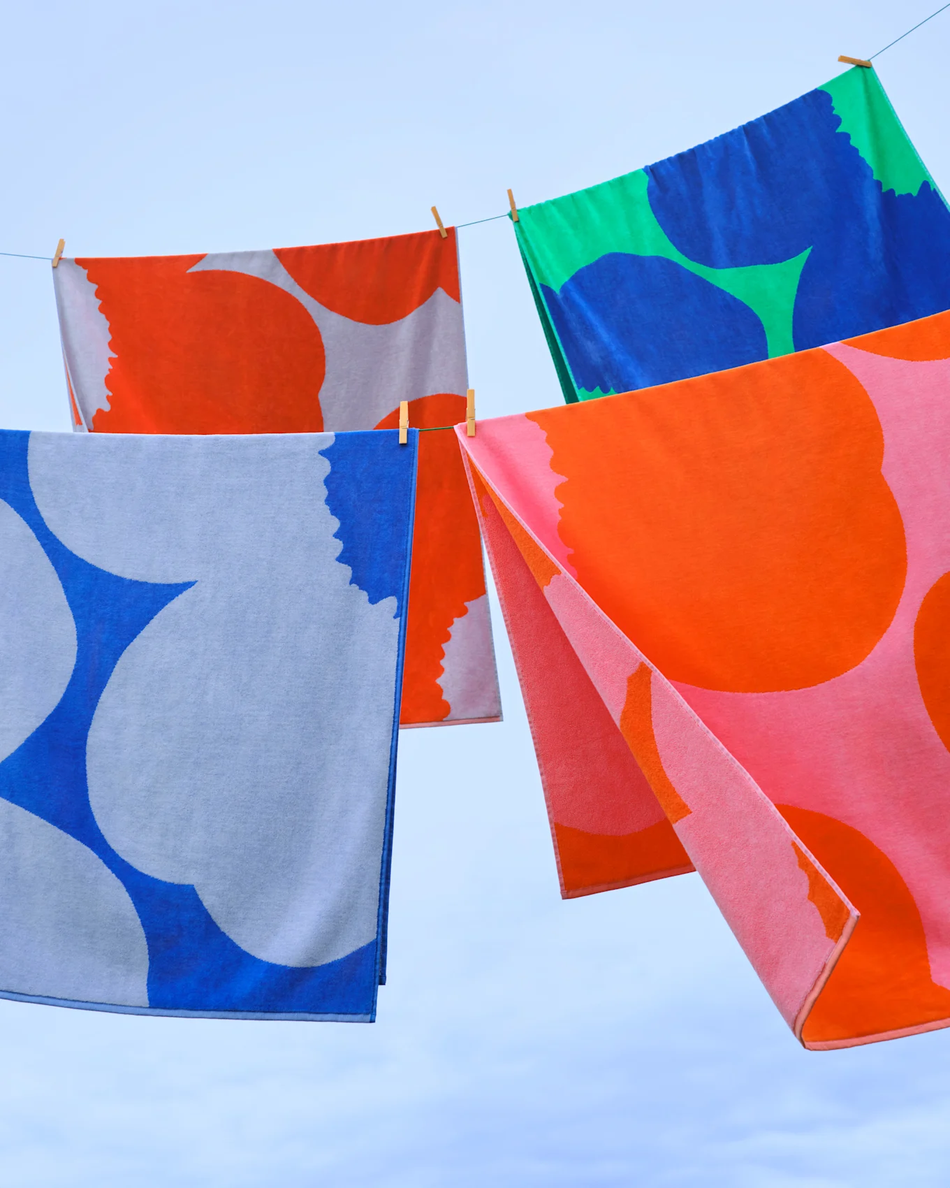 Colorful patterned towels hanging on a clothesline against a blue sky.