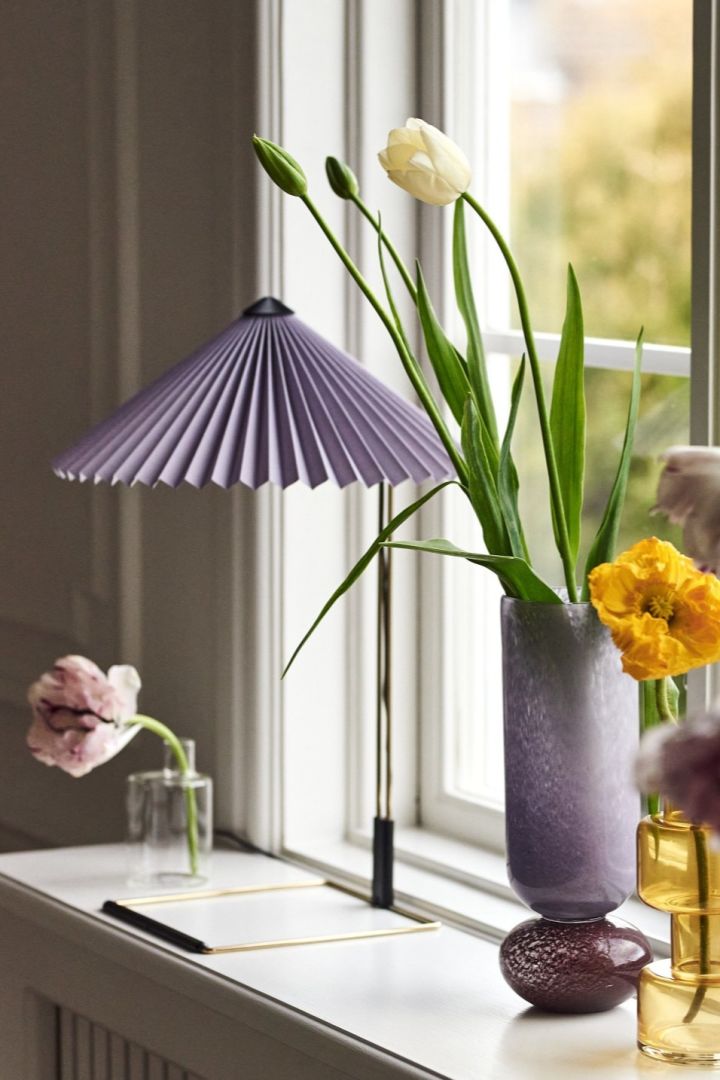 Spring interior trends 2023 offer retro-style pleated lamps, which we like to decorate with the trendy Matin table lamp from HAY with a purple pleated lampshade.