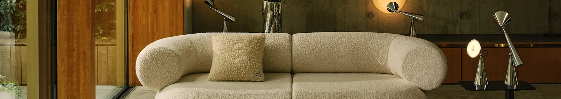 Modern living room with an off-white boucle modular sofa, a light patterned rug, and metal lamps.