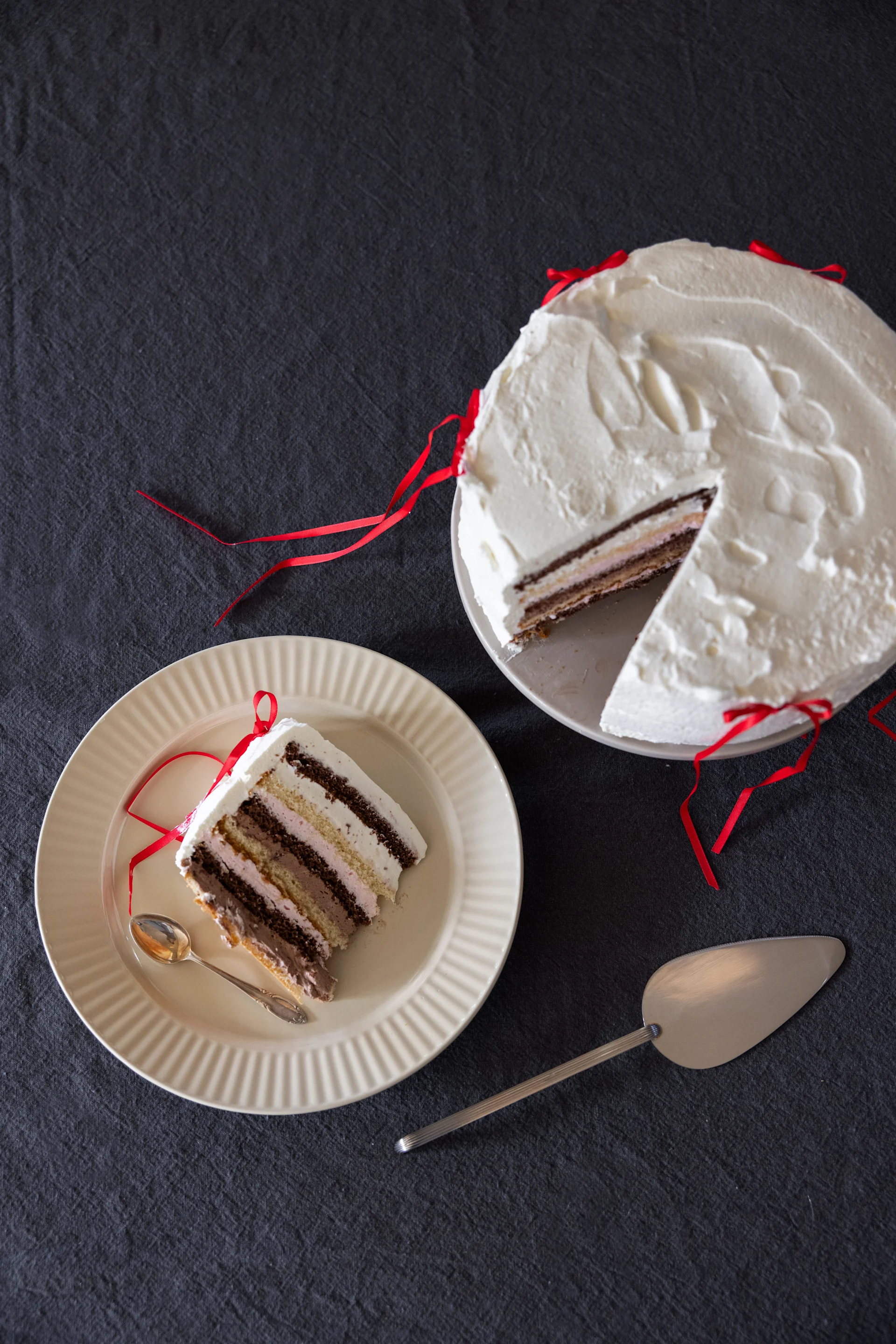 A cream cake on a plate, next to it a slice of cake on another plate from the Coffee & more collection by Sagaform in beige.