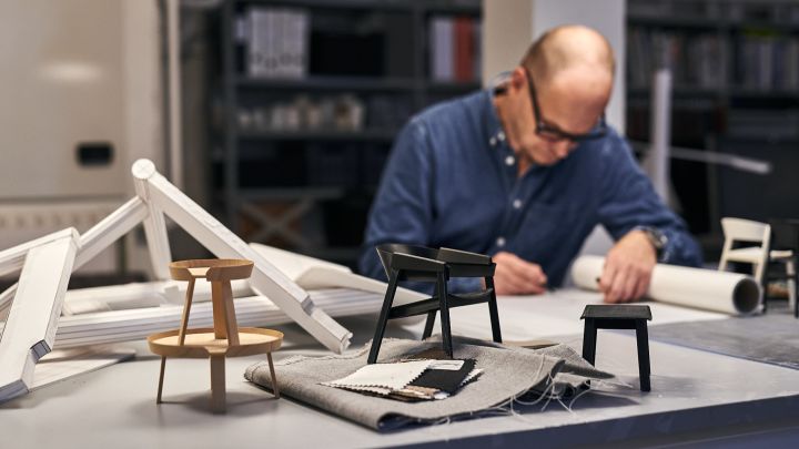 Thomas Bentzen sketches in his studio in Copenhagen with prototypes of the Cover chair and Around table around him.