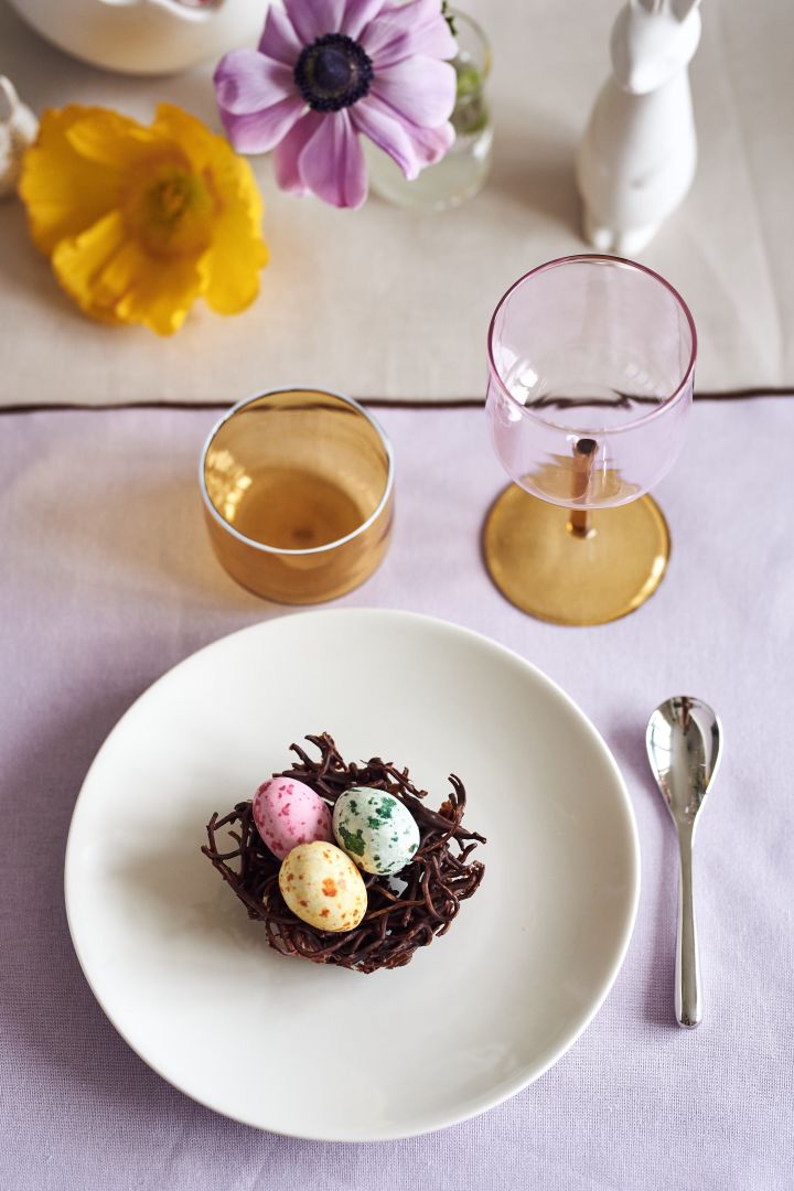 Create a festive Easter table setting in the spring pastels with a chocolate bird nests on an Arabia plate together with Tint glass and wine glasses from HAY.