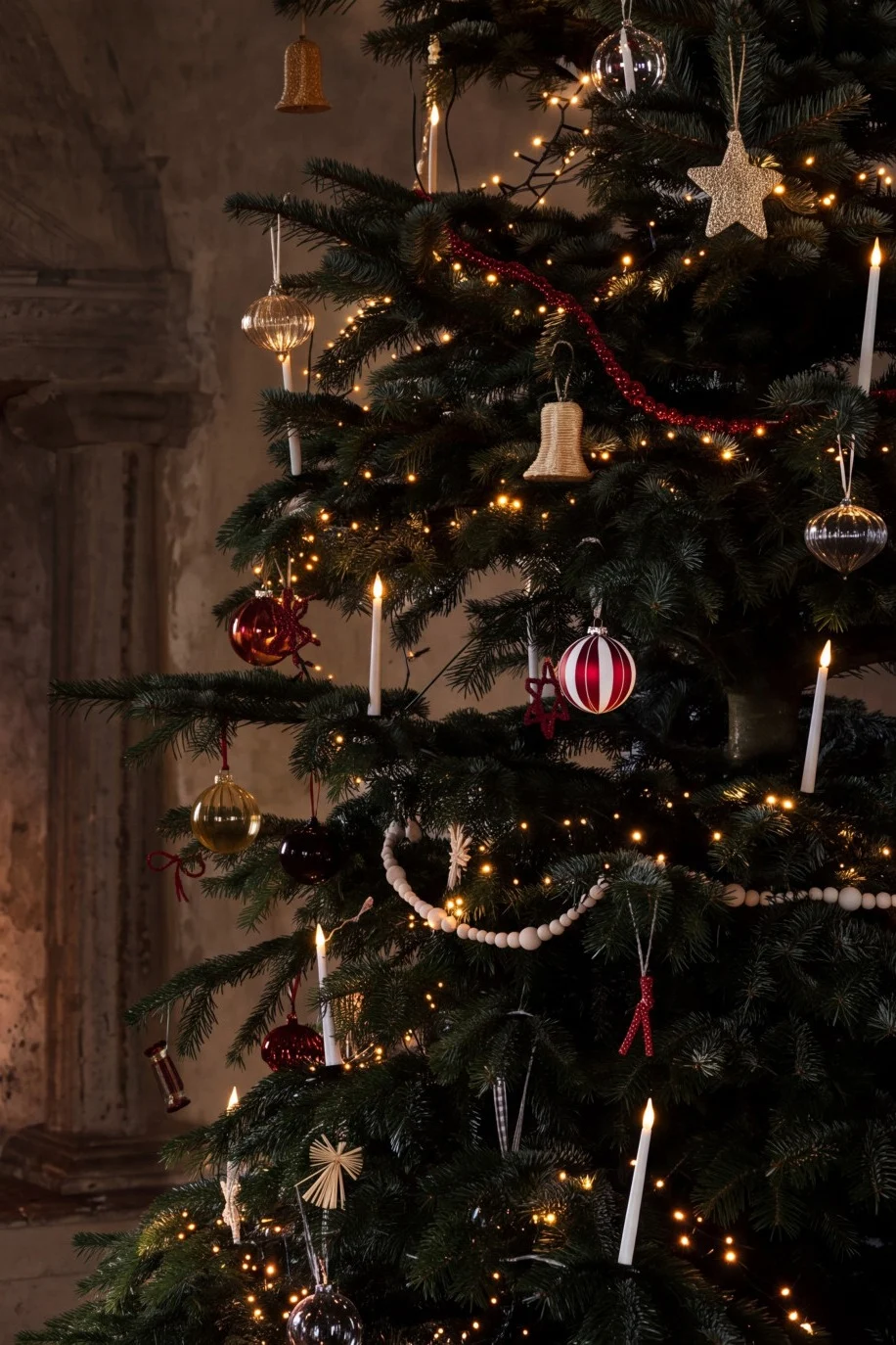 A decorated Christmas tree with lights and baubles next to a cozy fireplace with a burning fire.