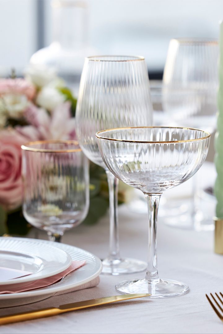 The glasses from the Palermo collection by Lyngby Glas have an elegant golden rim and are shown here on a stylishly laid table in white, pink and gold.