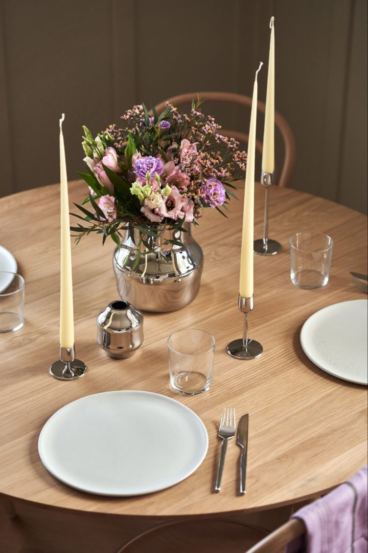 An elegant table setting with a polished stainless-steel vase from the Dorotea collection for Gense and matching candle sticks. 