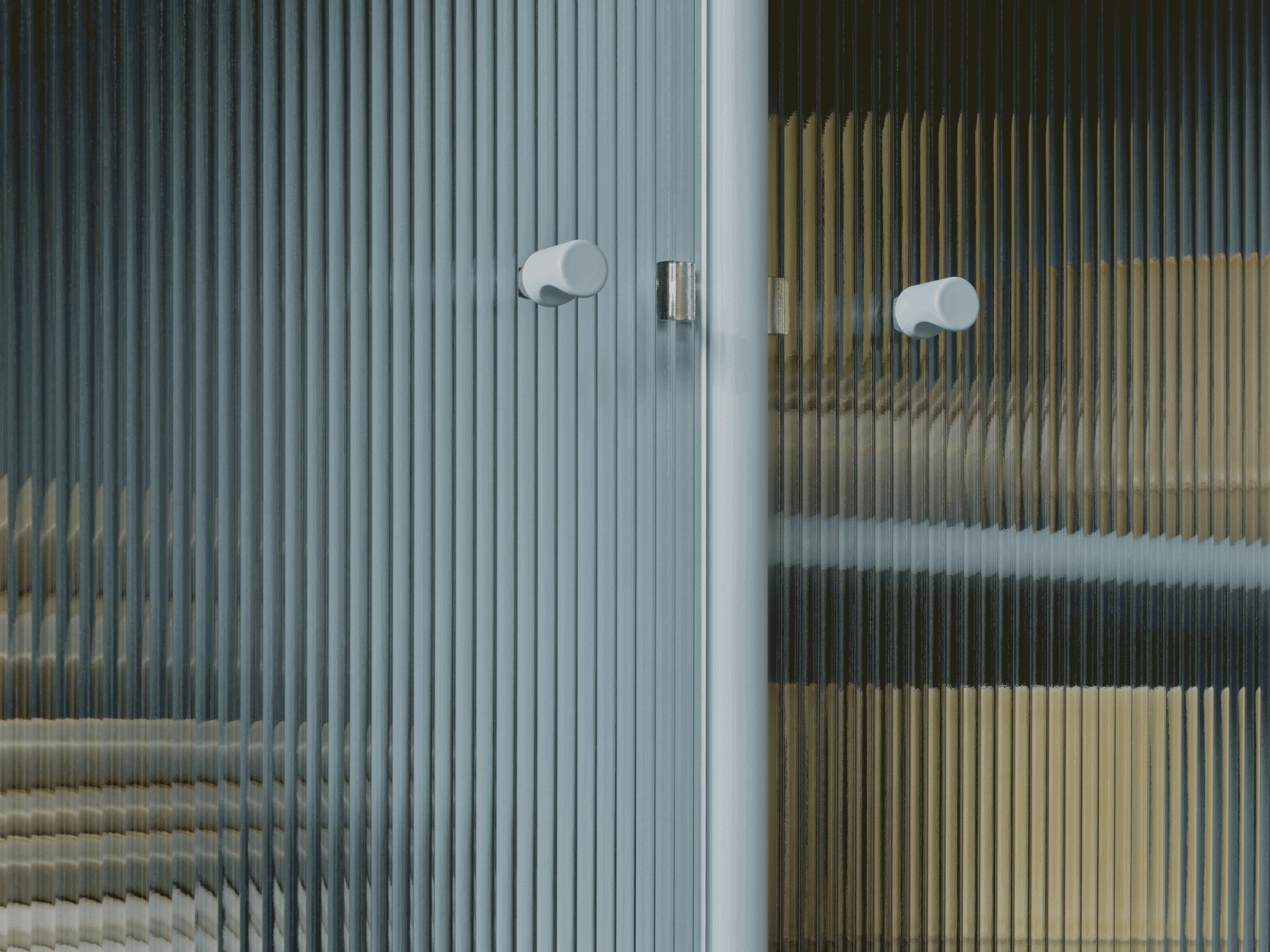 Close-up of a fluted glass door with two light-colored round handles, showing distorted colors through the translucent texture.