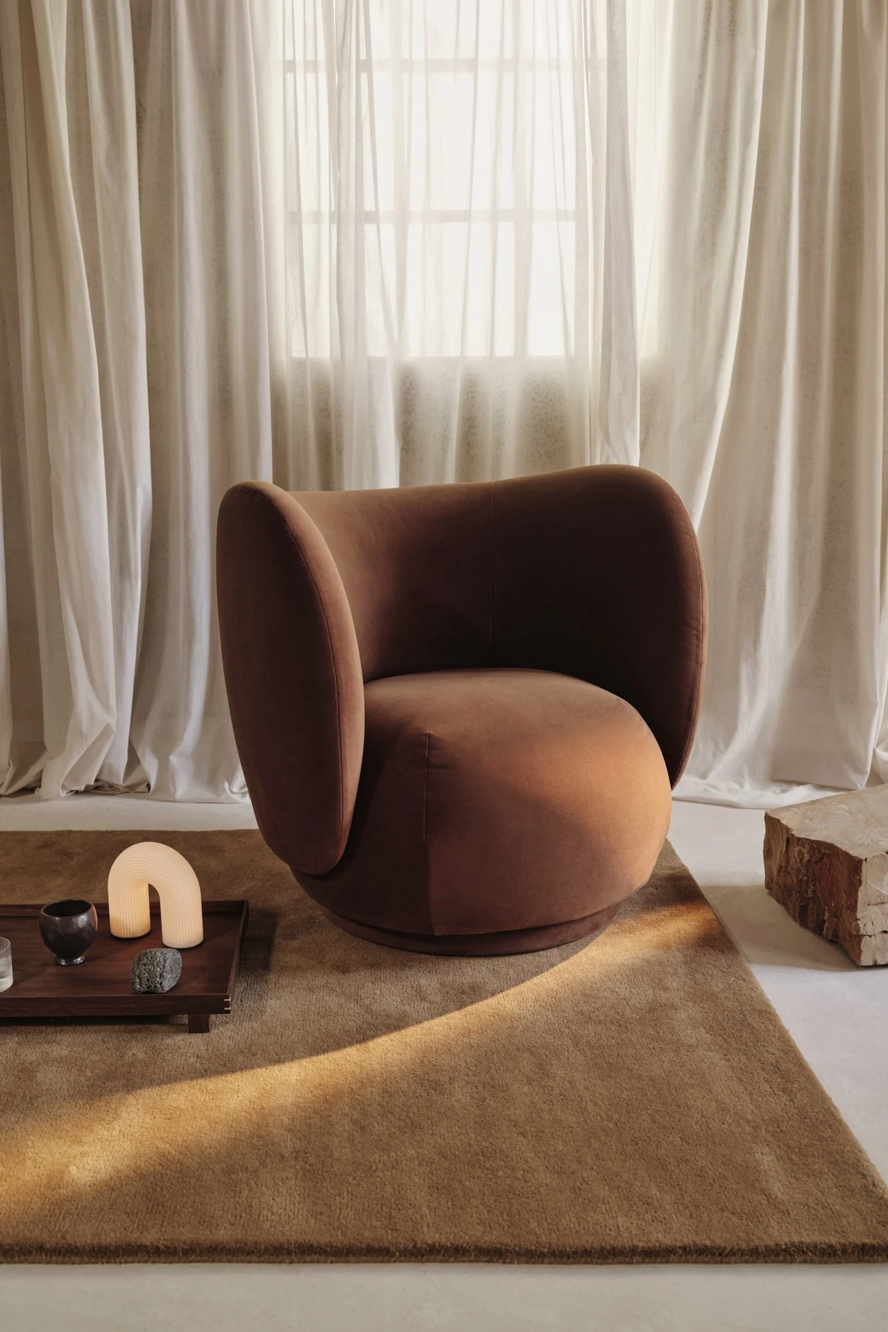 A brown velvet armchair sits in a minimalist room, reflecting the interior design trends of 2026.