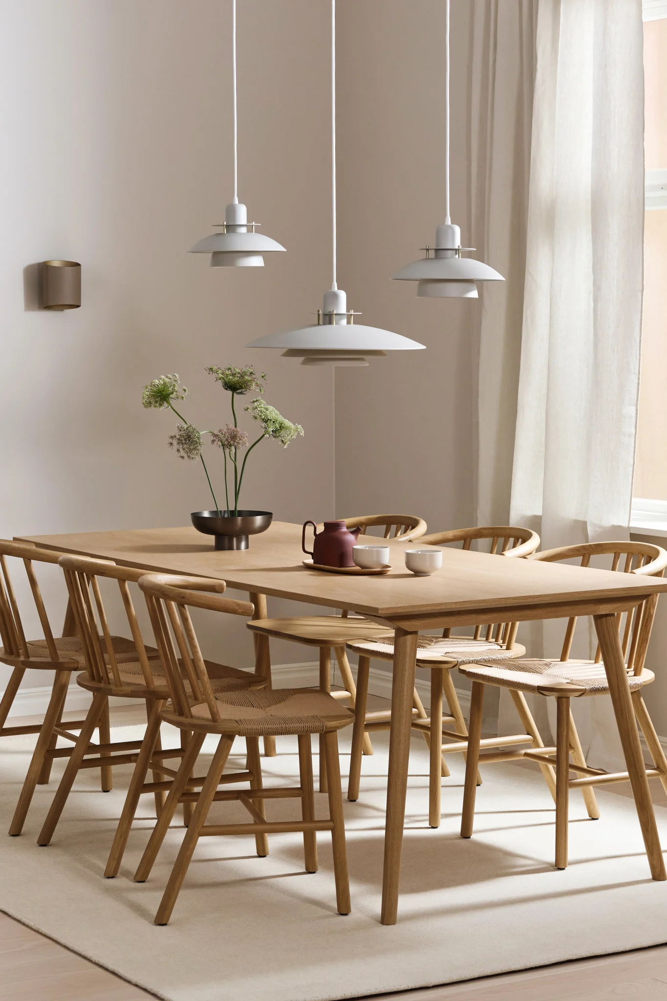 Here you see dining room lighting ideas for a long table. The Picasso lamp hangs in a row of three and the Sinne lamp hangs on the wall.